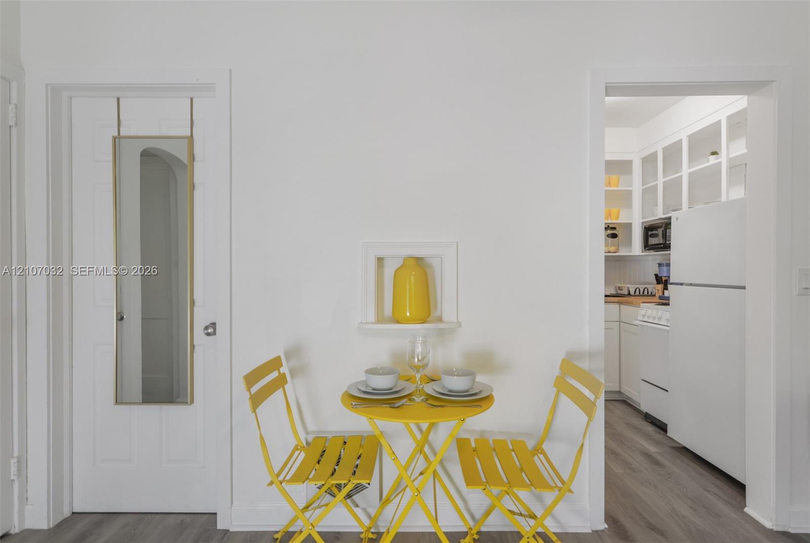 Built-in wall niche, wood-finish flooring, white cabinetry with glass-front uppers, and six-panel interior door