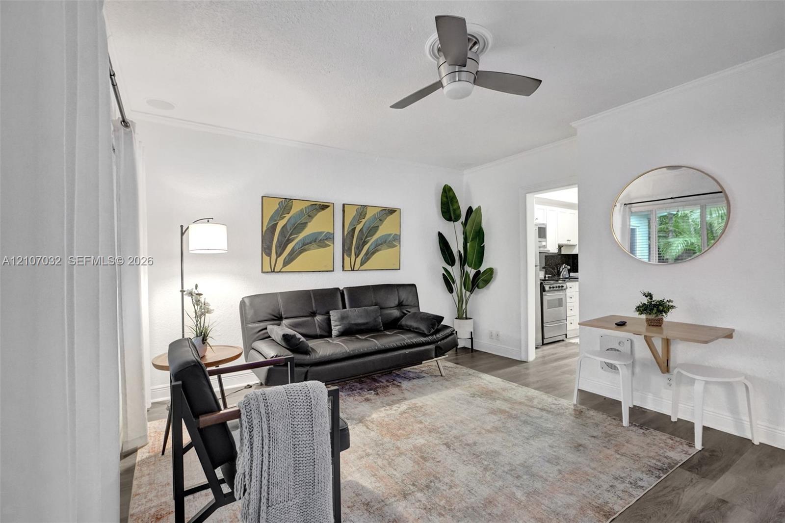 Living area featuring wood-finish flooring, a neutral color palette, and a modern ceiling fan with integrated lighting