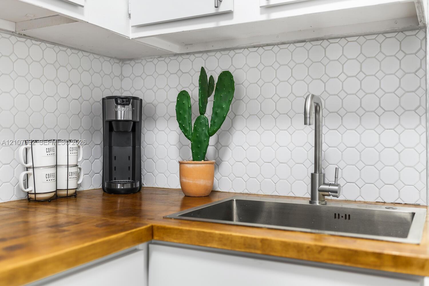 Butcher block countertops, white hexagonal tile backsplash, stainless steel undermount sink, and a gooseneck faucet