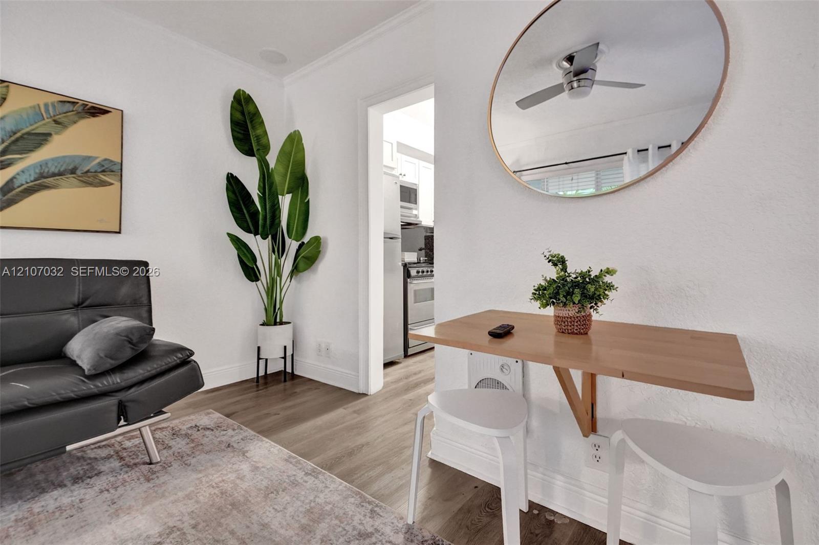 Interior space featuring wood-finish flooring, a wall-mounted fold-down desk, and a circular wall mirror