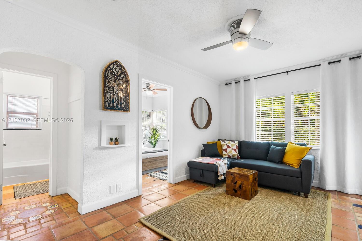Terra cotta tile flooring, arched doorway, recessed wall niche, and brushed nickel ceiling fan