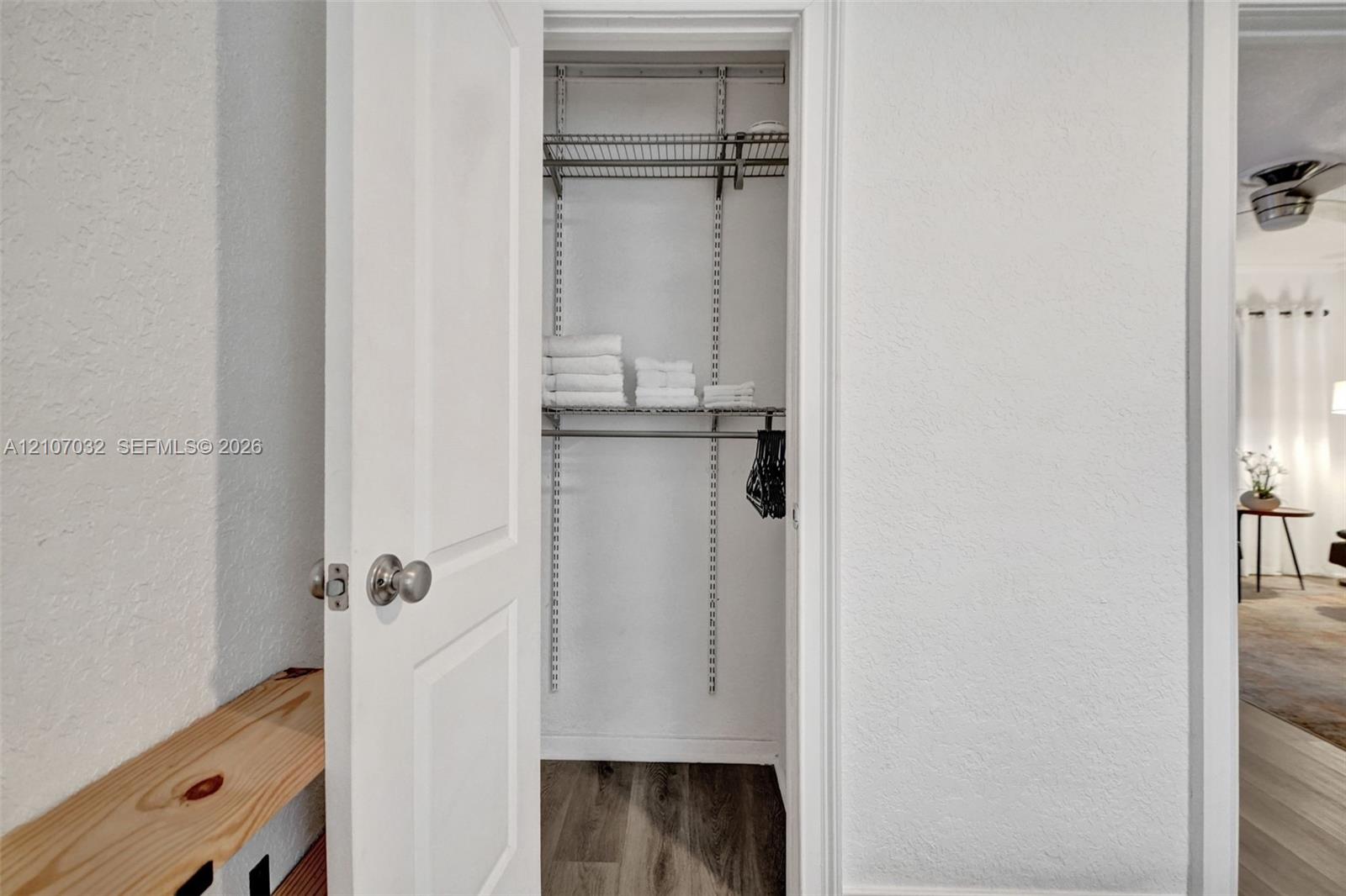 Reach-in closet featuring adjustable metal shelving and wood-finish flooring