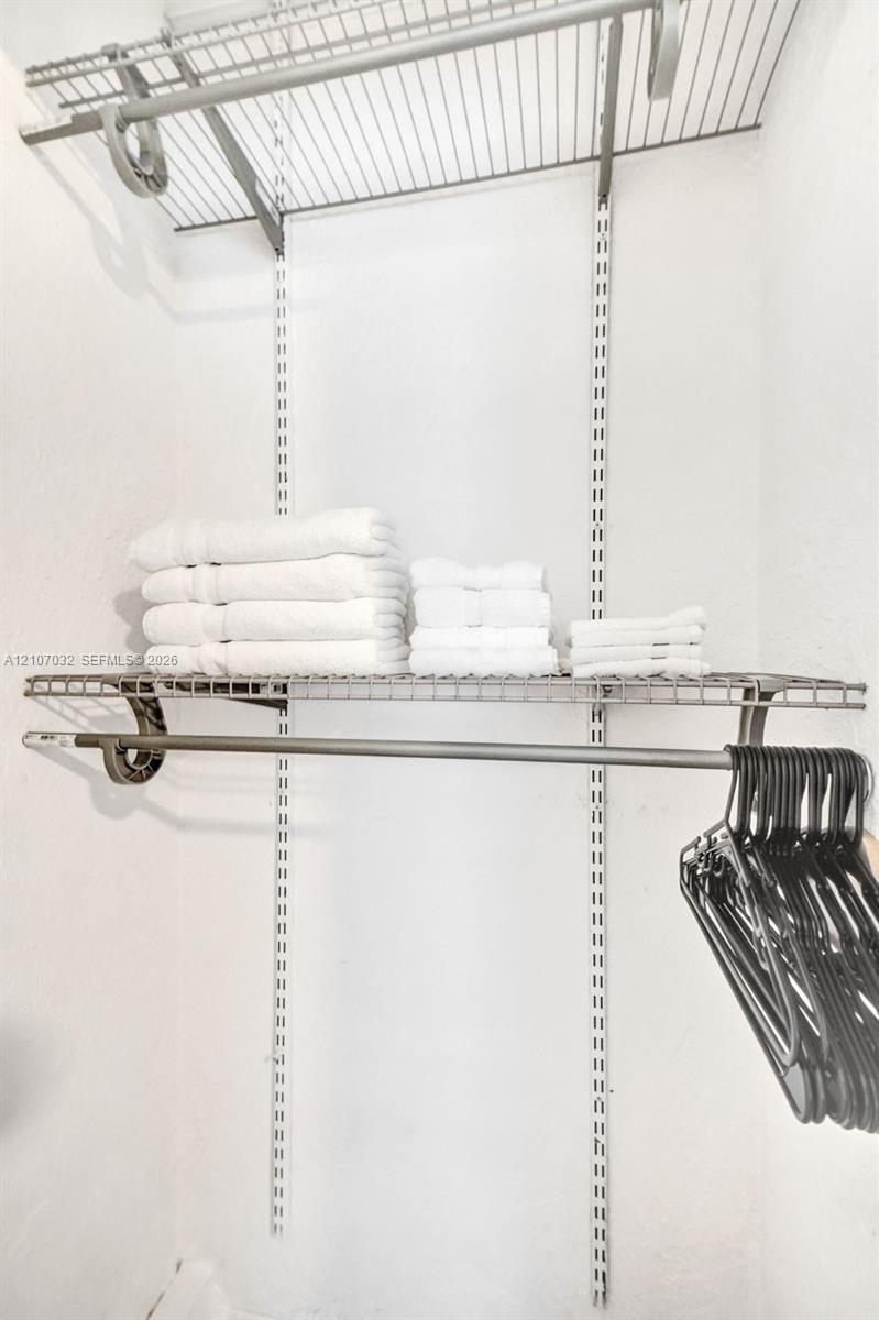 Adjustable storage system featuring white wire shelving, wall-mounted tracks, and an integrated hanging rod