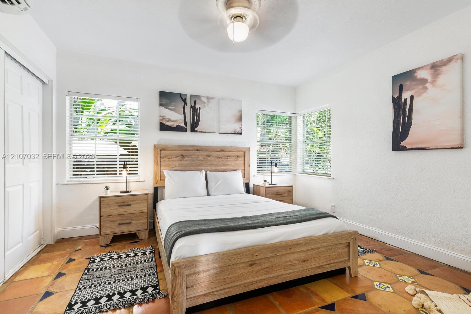 Interior space featuring terracotta floor tile, dual-aspect windows with horizontal blinds, and a ceiling-mounted light fixture with fan