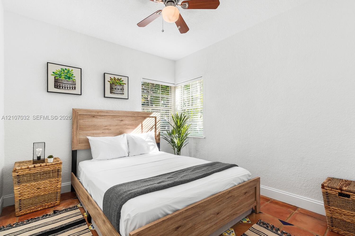 Room featuring terra-cotta tile flooring, corner windows with horizontal blinds, and a ceiling fan with integrated lighting