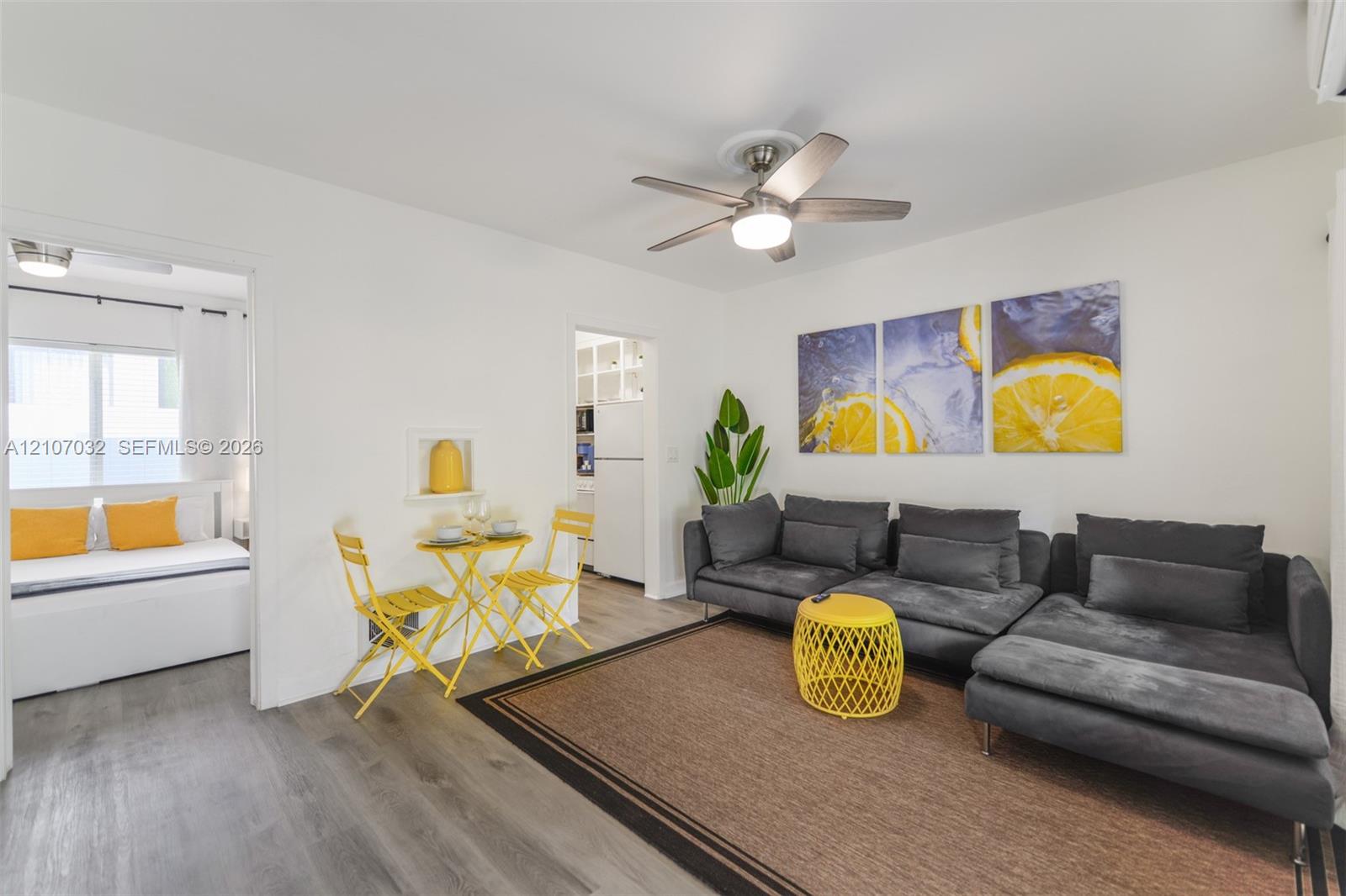 Living area featuring wood-finish flooring, a ceiling fan with integrated lighting, and a recessed wall niche