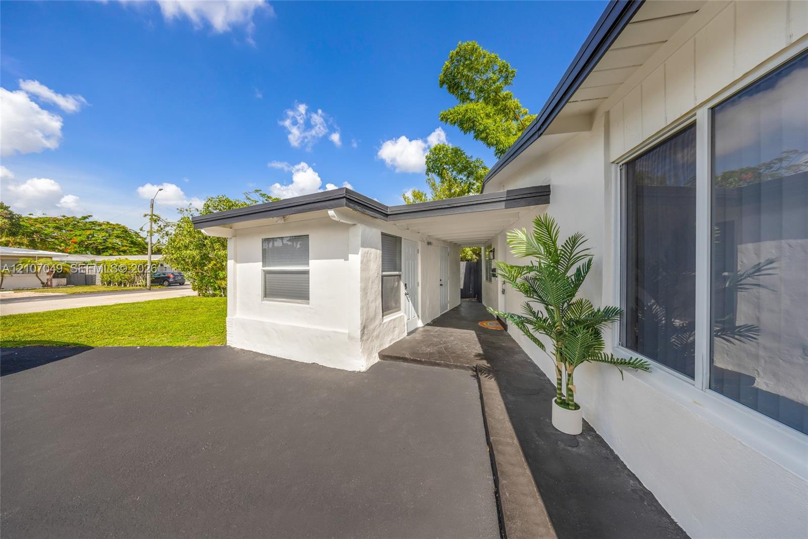 Exterior featuring a smooth-finish white facade, asphalt driveway, covered entryway, and large-pane windows with dark framing