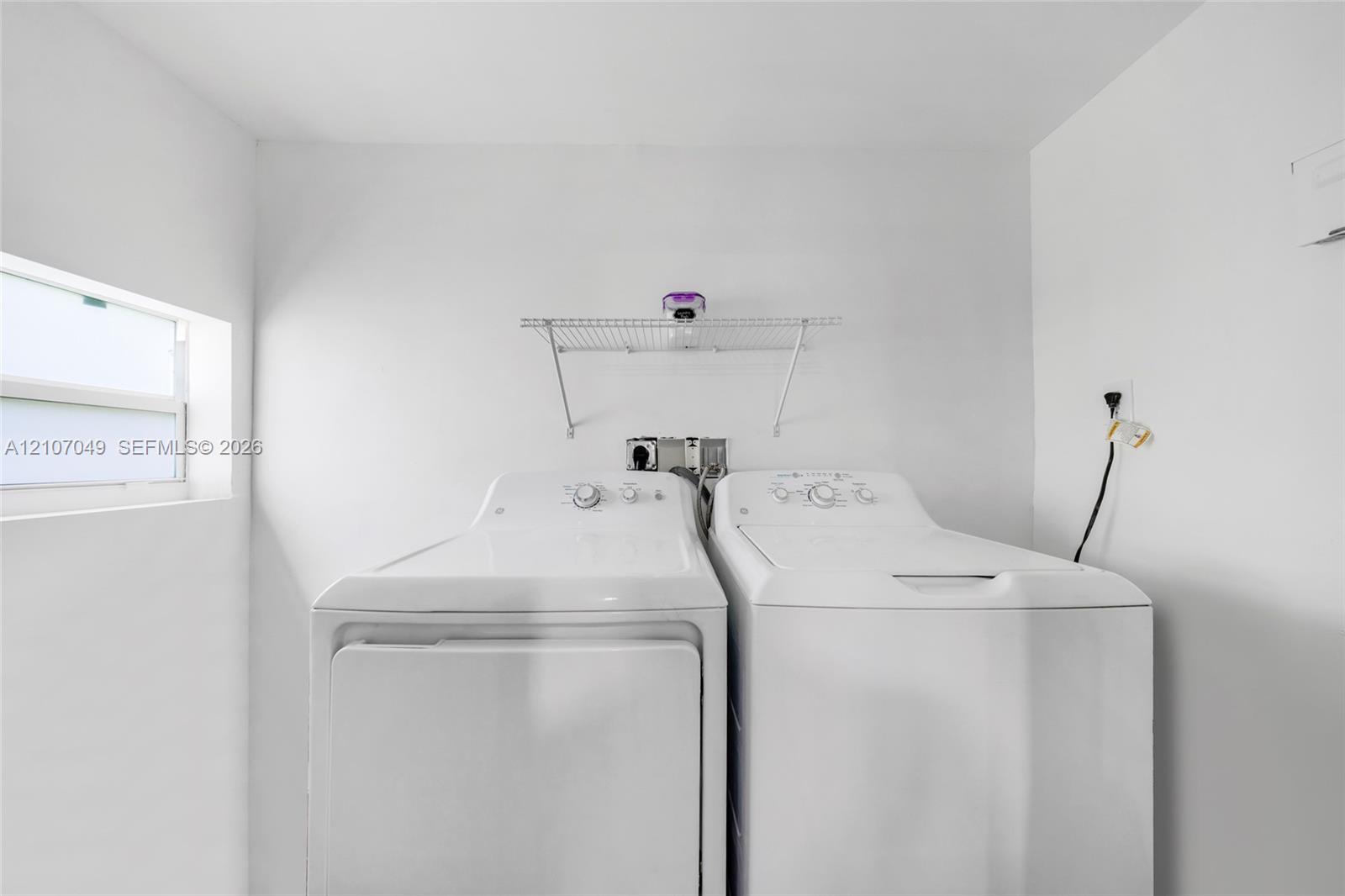 Laundry area featuring a window, built-in wire shelving, and dedicated utility hookups