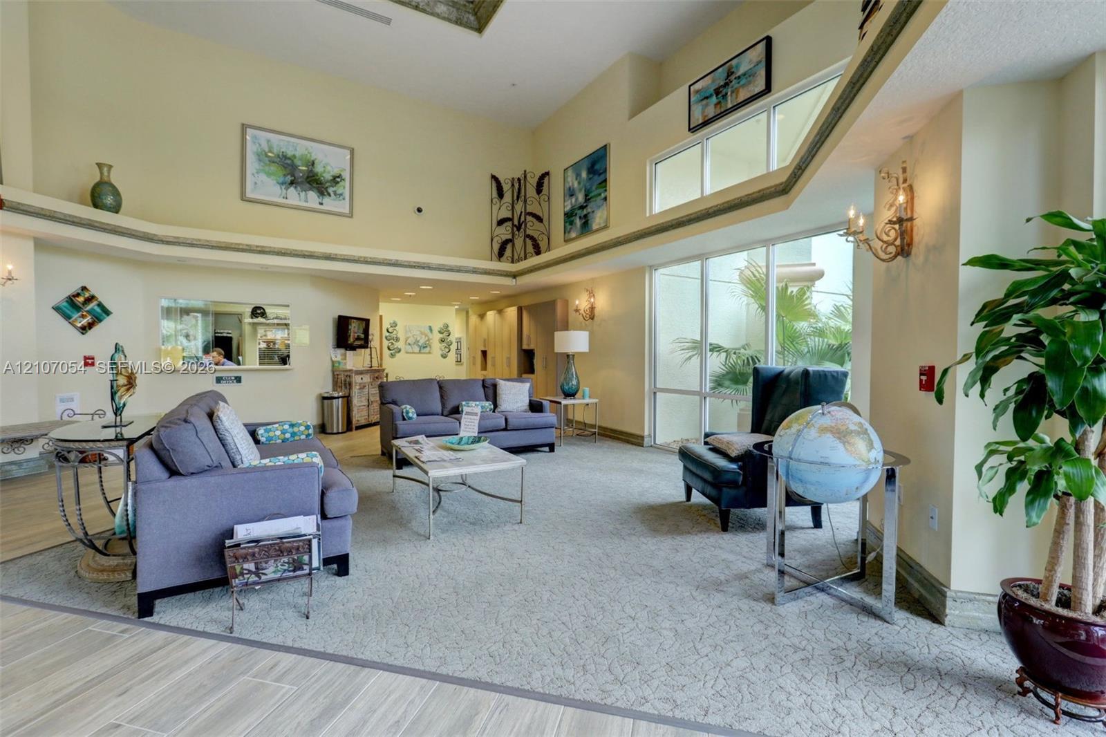 Clubhouse: Open-concept room featuring vaulted ceilings, floor-to-ceiling windows, built-in shelving, decorative wall-mounted lighting, and neutral-tone carpeting