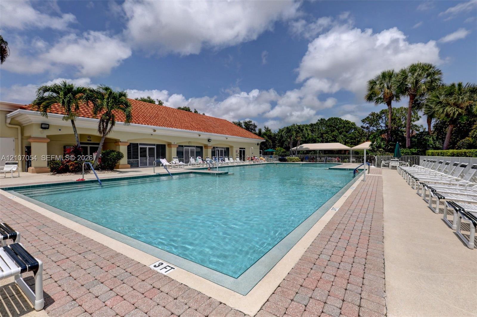 Swimming pool with stepped entry, surrounding brick paver decking, and a terracotta tile roof structure