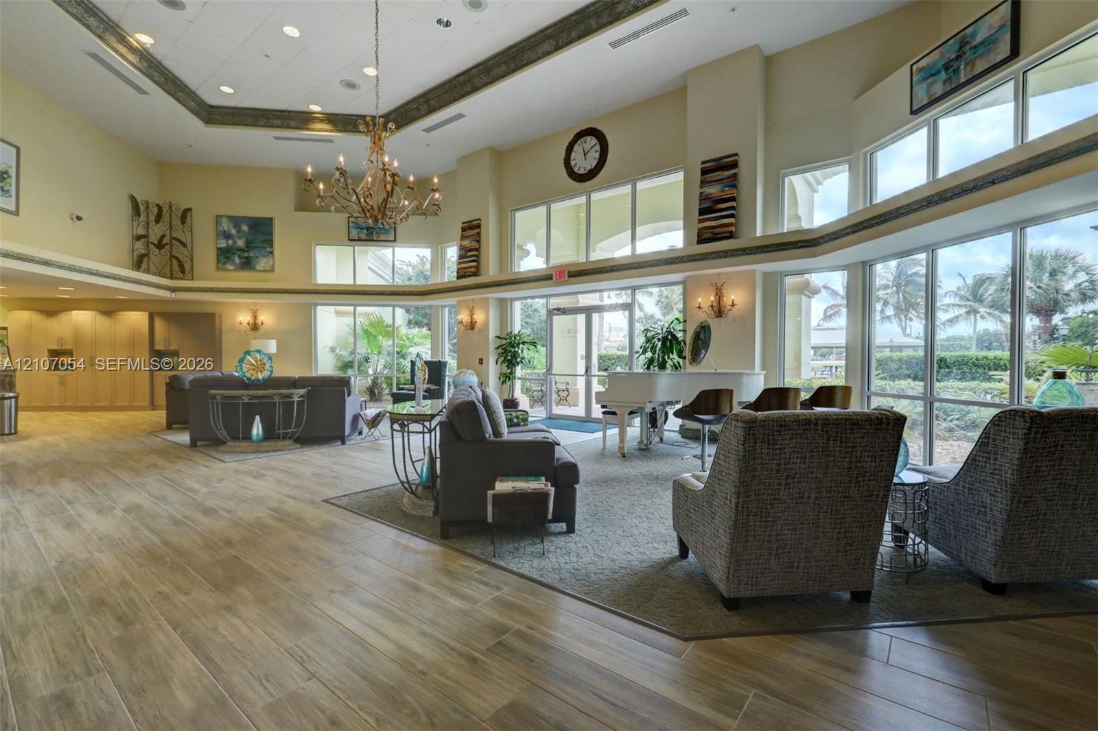 Clubhouse - Expansive common area featuring vaulted ceilings, floor-to-ceiling windows, wood-finish flooring, recessed lighting, and a decorative chandelier