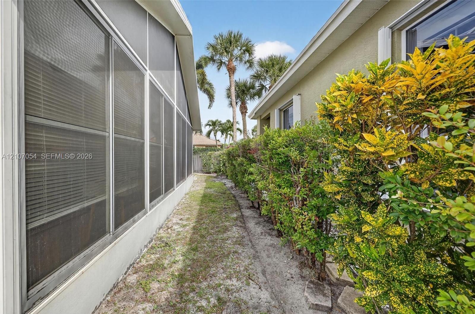 Side yard featuring concrete foundation, stucco siding, and mature landscaping