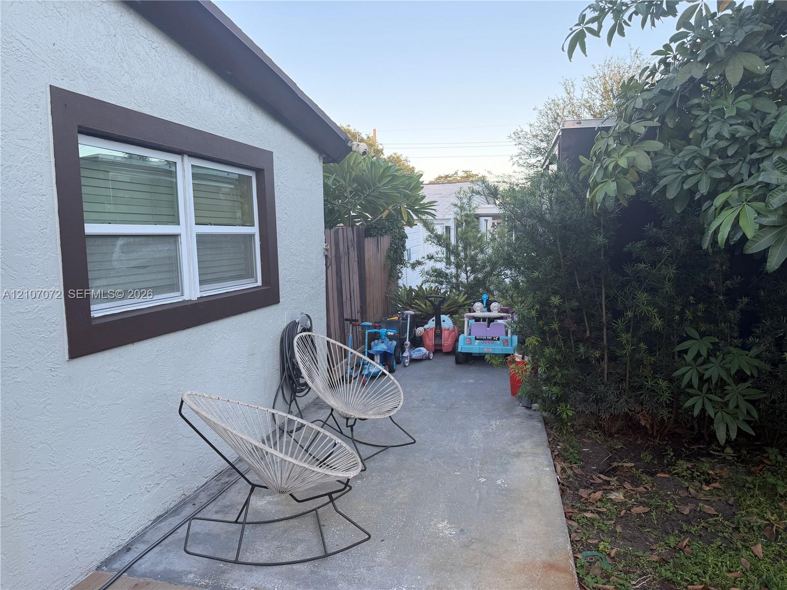 Stucco exterior siding, double-pane window with dark trim, and concrete patio area