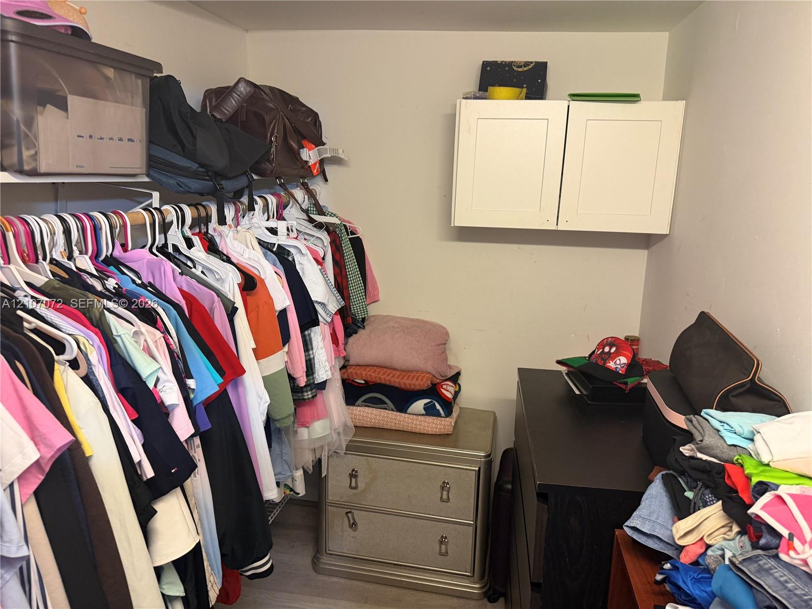 Storage area featuring white wall-mounted upper cabinetry and wire shelving systems