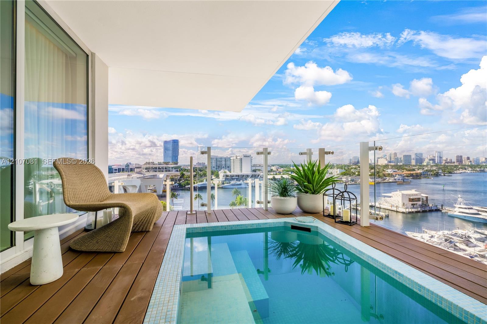 Covered balcony featuring an inset plunge pool, wood-finish decking, and a glass-paneled railing