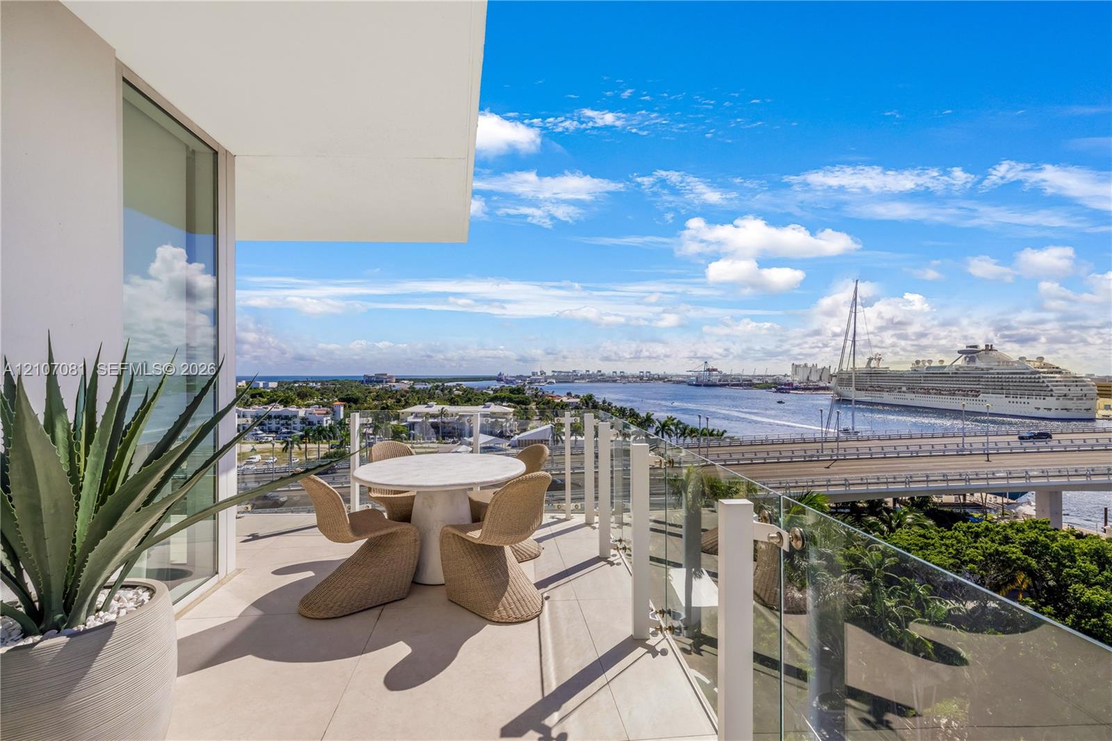 Covered balcony featuring oversized porcelain tile flooring and a transparent glass railing overlooking a waterway