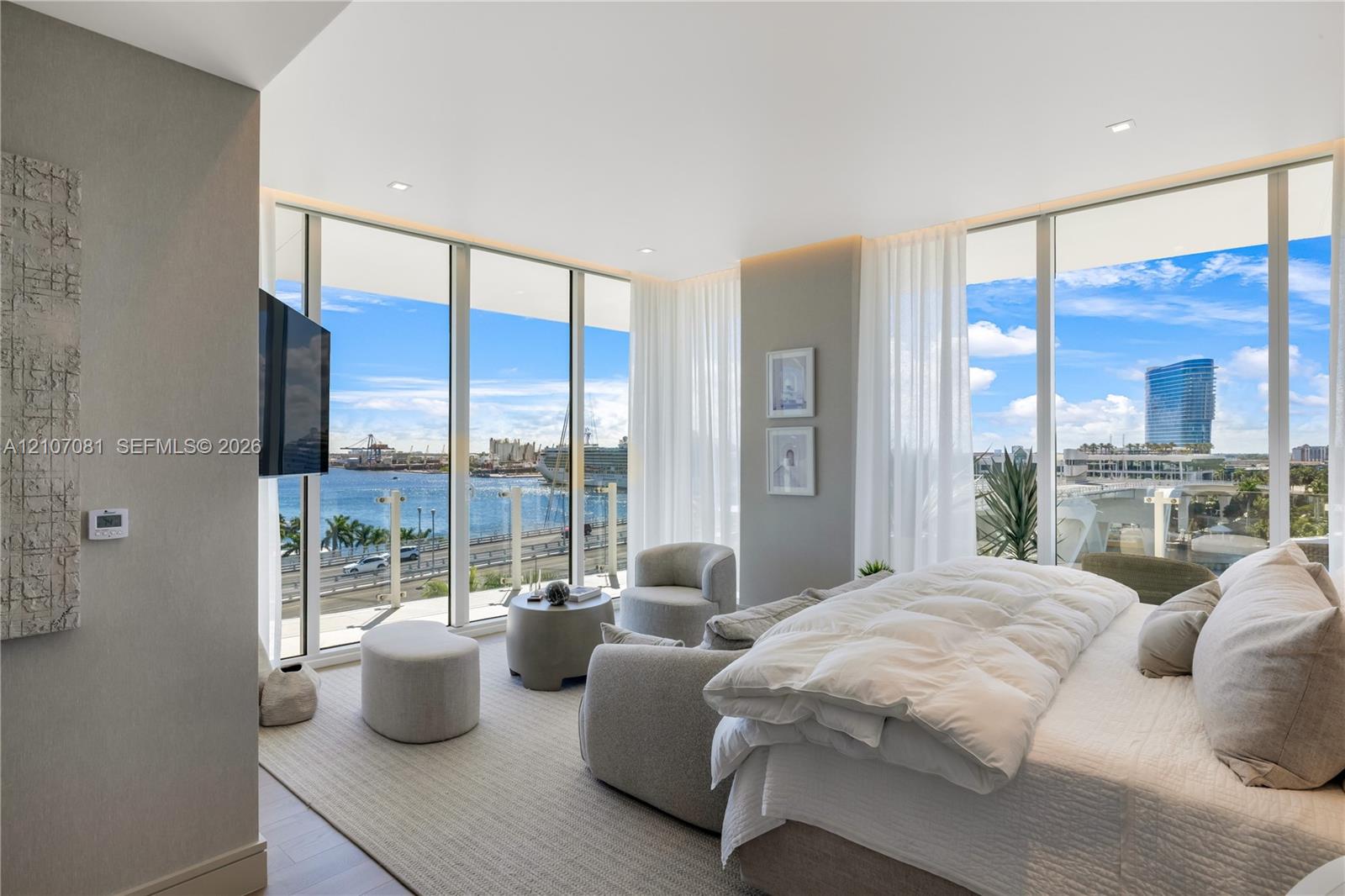 Floor-to-ceiling windows, neutral carpeting, recessed lighting, and a glass-paneled balcony