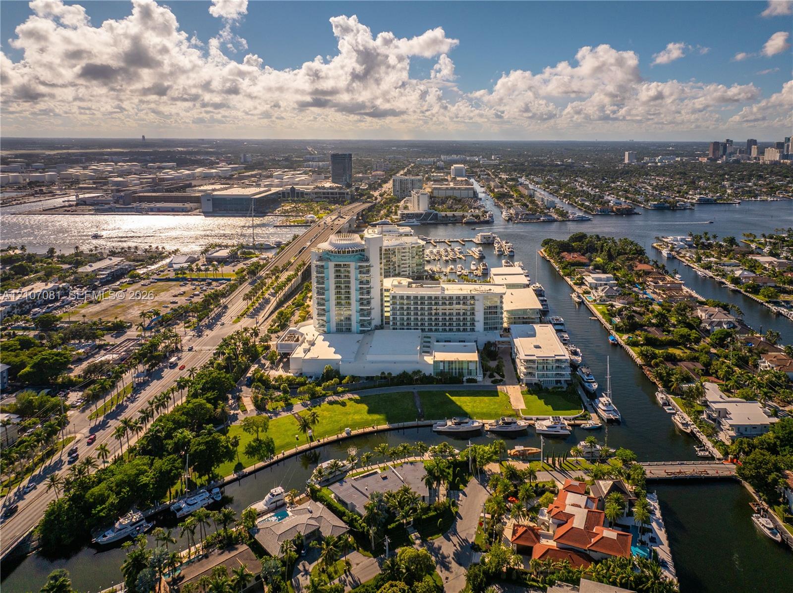 Aerial perspective featuring a high-rise residential structure, deep-water canal access, private boat slips, extensive waterfront, and proximity to coastal waterways