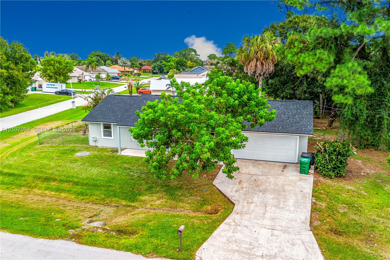 Single-story residence featuring a shingle roof, attached two-car garage, concrete driveway, and established landscaping