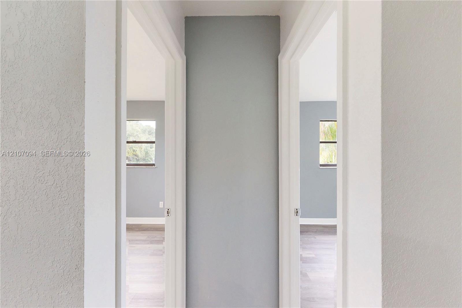 Interior hall featuring neutral-toned walls, wood-finish flooring, and two entryways with white door casings