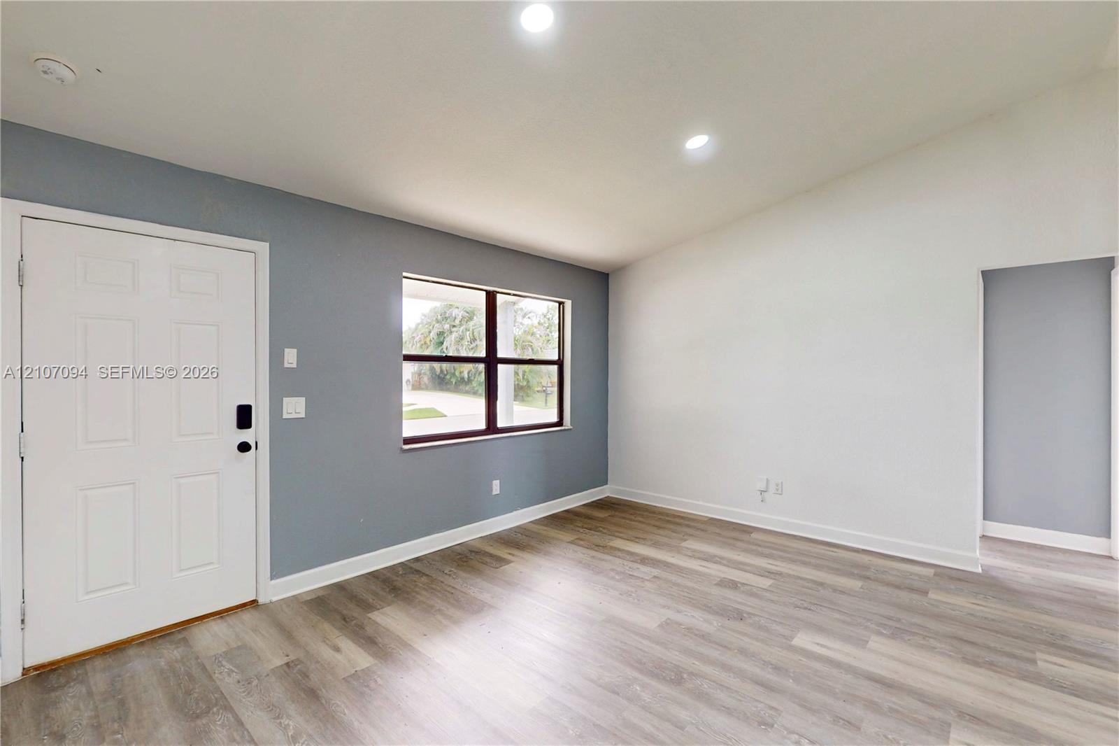 Vaulted ceilings, wood-finish flooring, recessed lighting, and a multi-pane window