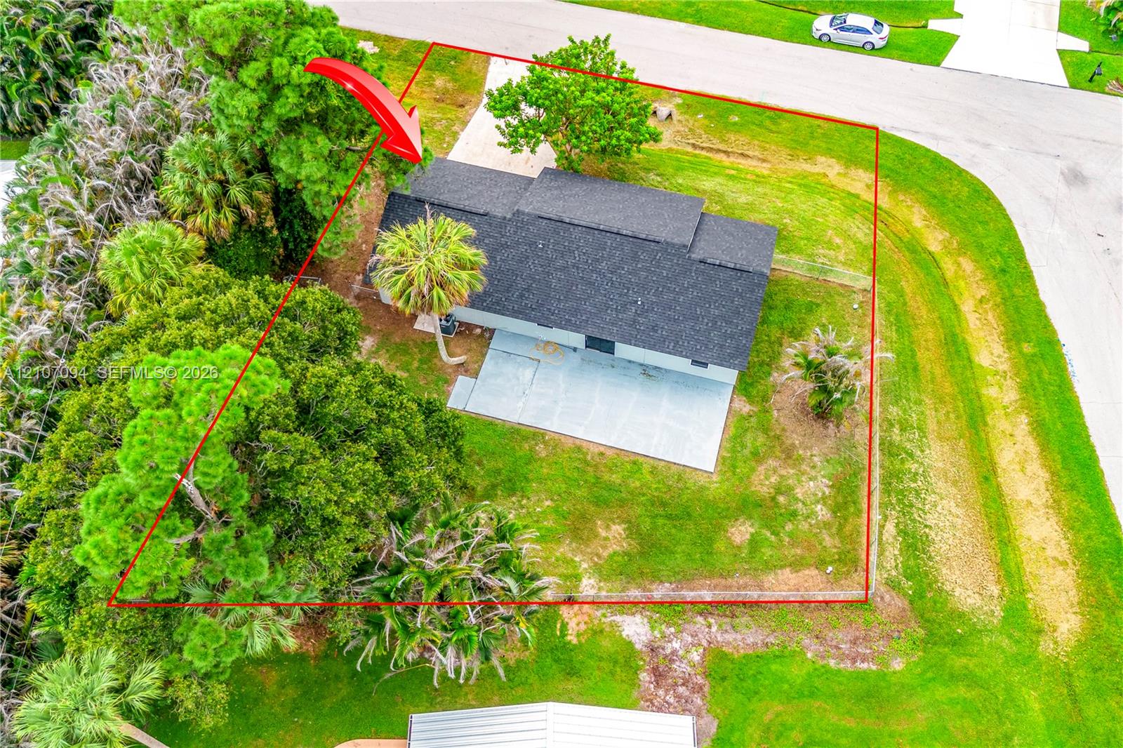 Aerial perspective of a property featuring a corner lot, a concrete patio, mature trees, and landscaping