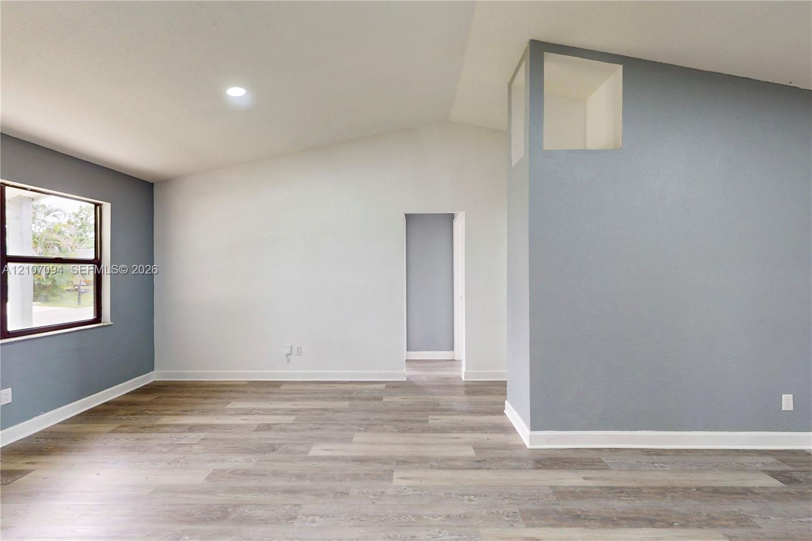 Vaulted ceilings, wood-finish flooring, recessed lighting, and a prominent architectural niche