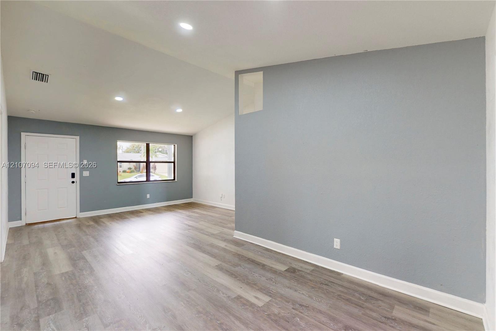 Interior space featuring vaulted ceilings, wood-finish flooring, recessed lighting, and large windows with dark-finish frames