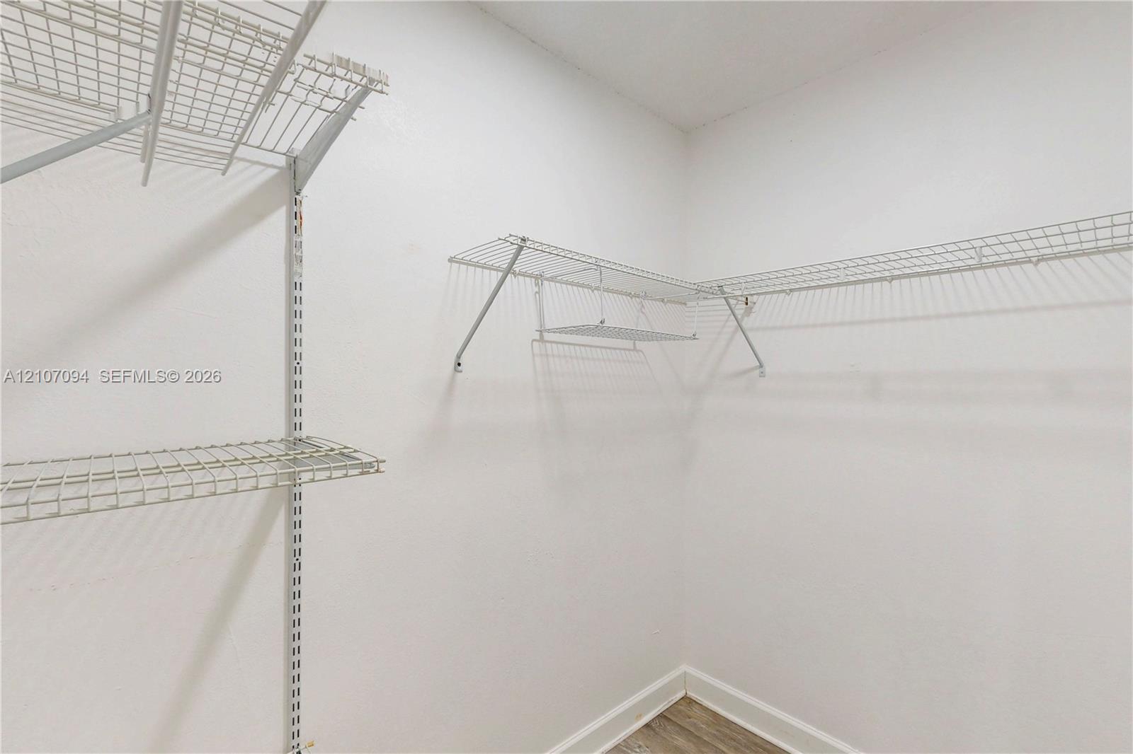 Storage area featuring wall-mounted wire shelving and wood-finish flooring