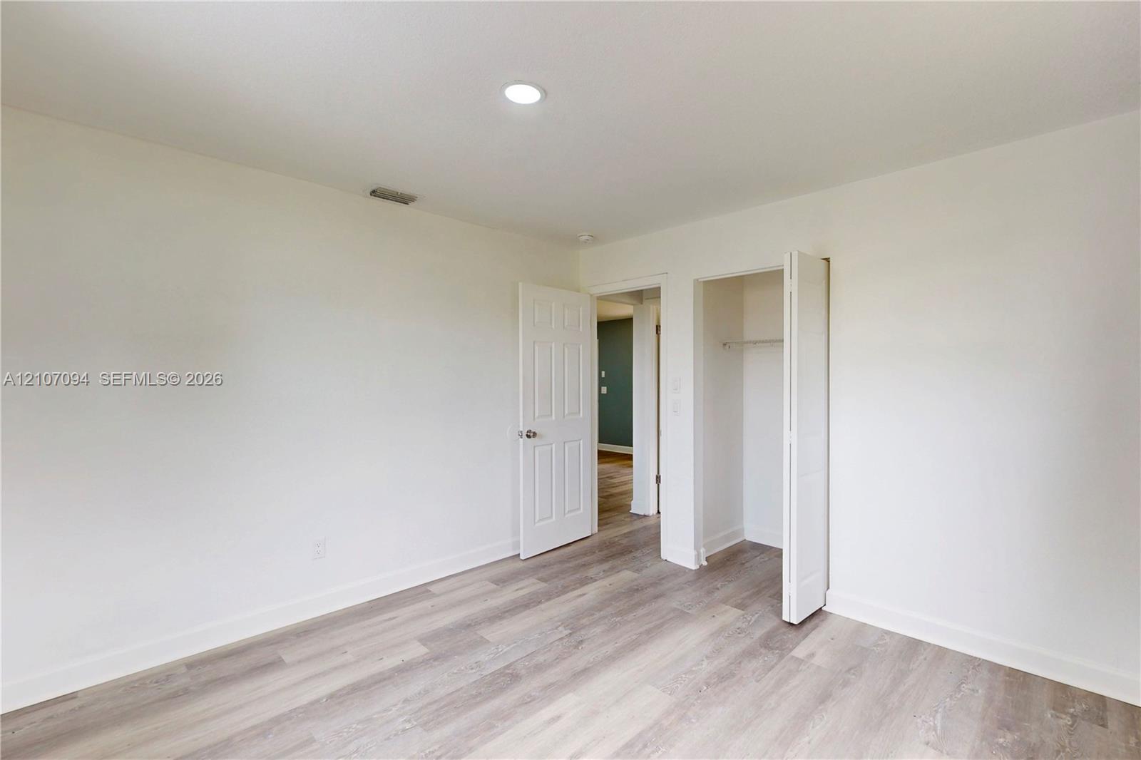 Room featuring wood-finish flooring, recessed lighting, and a closet with bifold doors