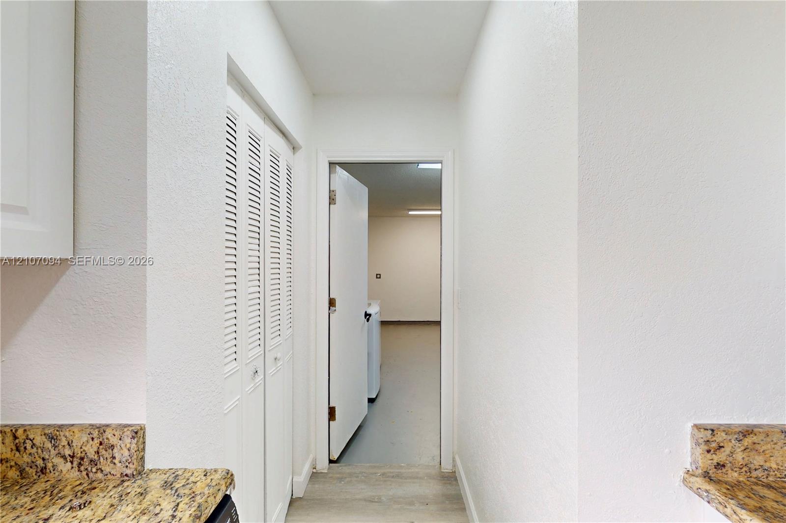 Textured stone-finish countertops, white louvered-door closet, and neutral wood-finish flooring