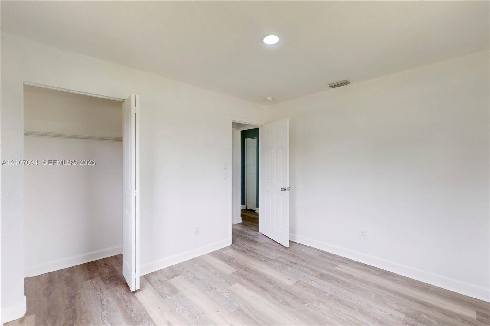 Interior space featuring wood-finish flooring, white walls, recessed ceiling lighting, and a closet with a bi-fold door