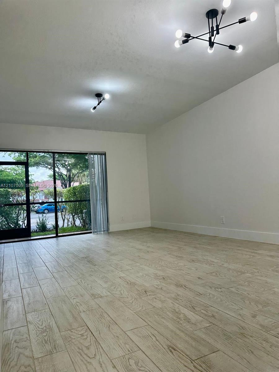 Room featuring wood-finish tile flooring, matte black multi-arm light fixtures, and a large sliding glass door with a screen enclosure