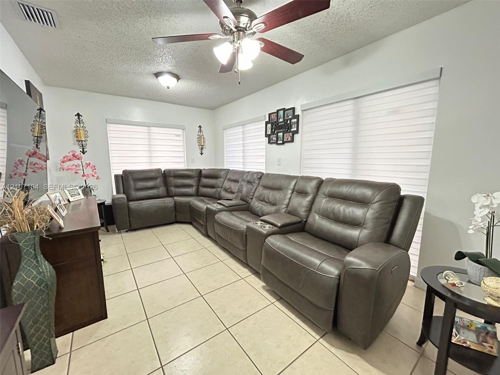 Neutral-tone ceramic tile flooring, multi-speed ceiling fan with integrated lighting, recessed lighting, and sheer roller shades
