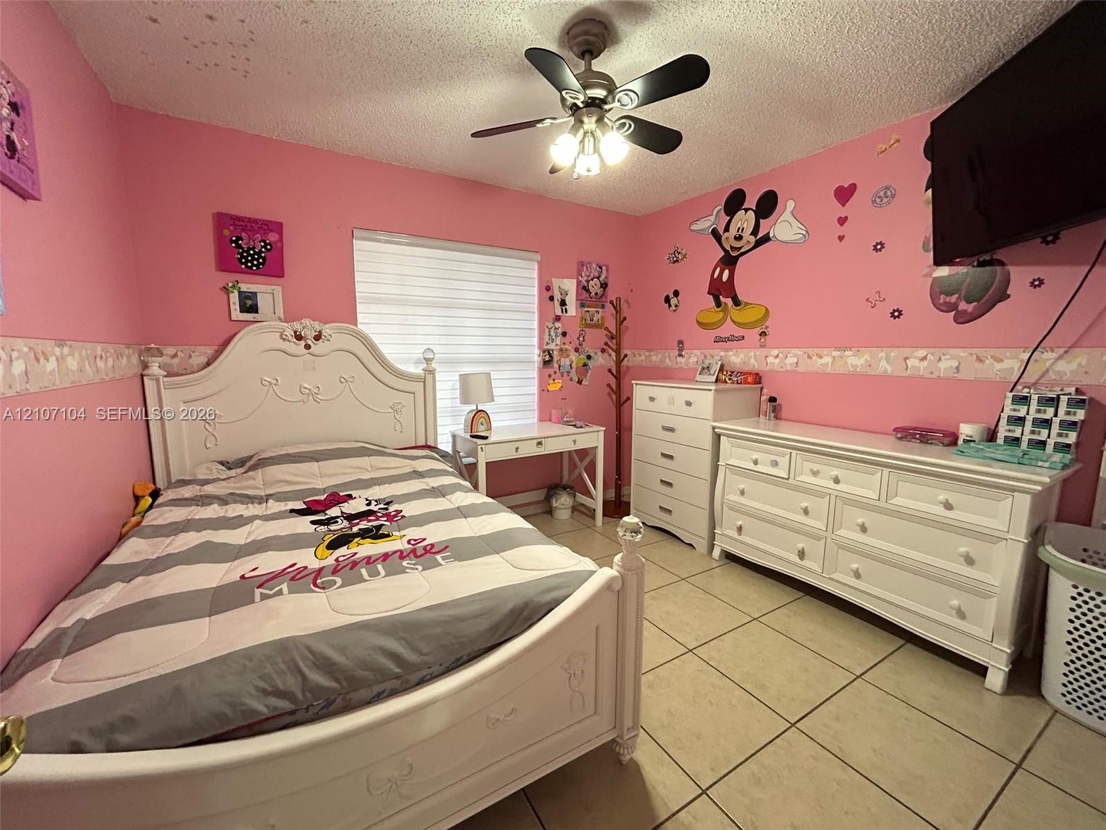 Room featuring neutral tile flooring, window with horizontal blind, and a central ceiling fan with integrated light fixture