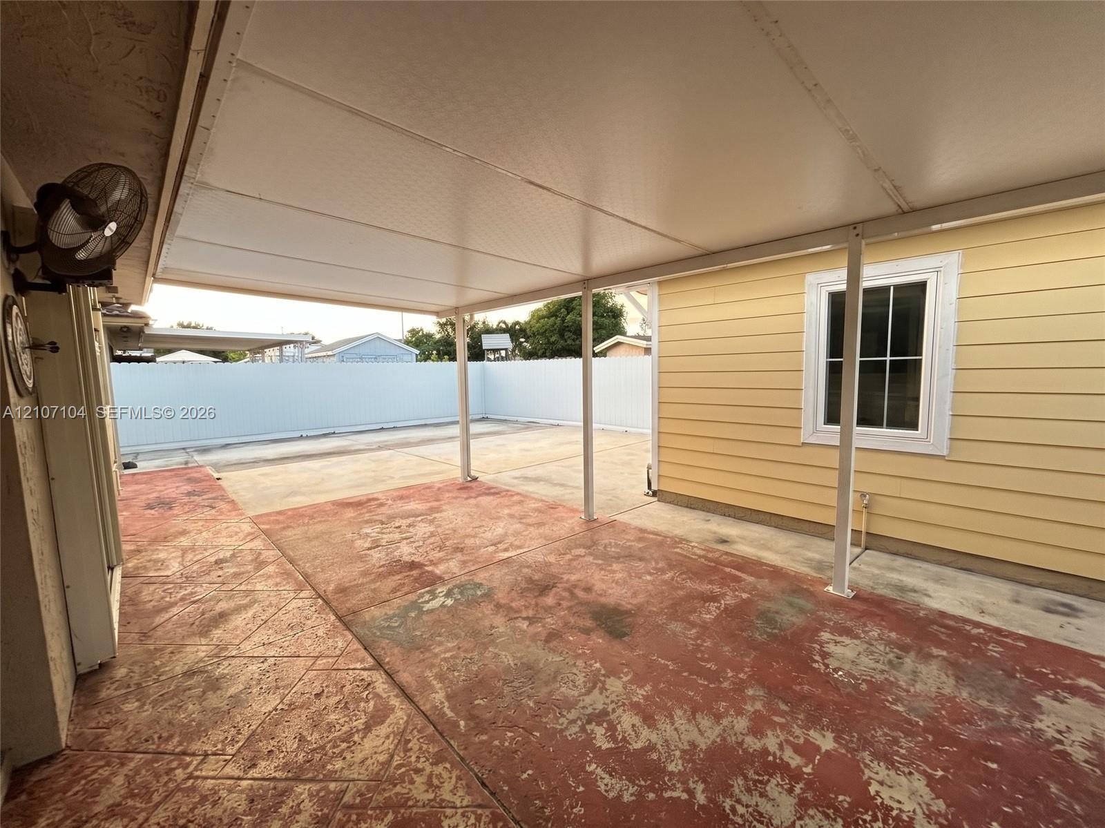 Covered patio featuring stamped concrete flooring, exterior lap siding, and a surrounding privacy fence