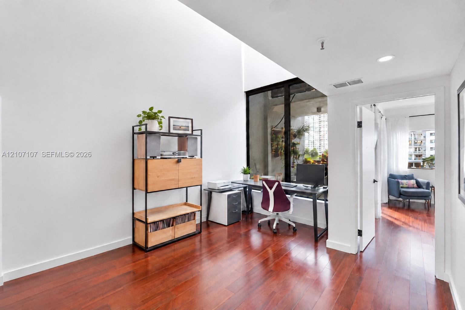High-ceiling interior space featuring floor-to-ceiling windows, recessed lighting, and wood-finish flooring