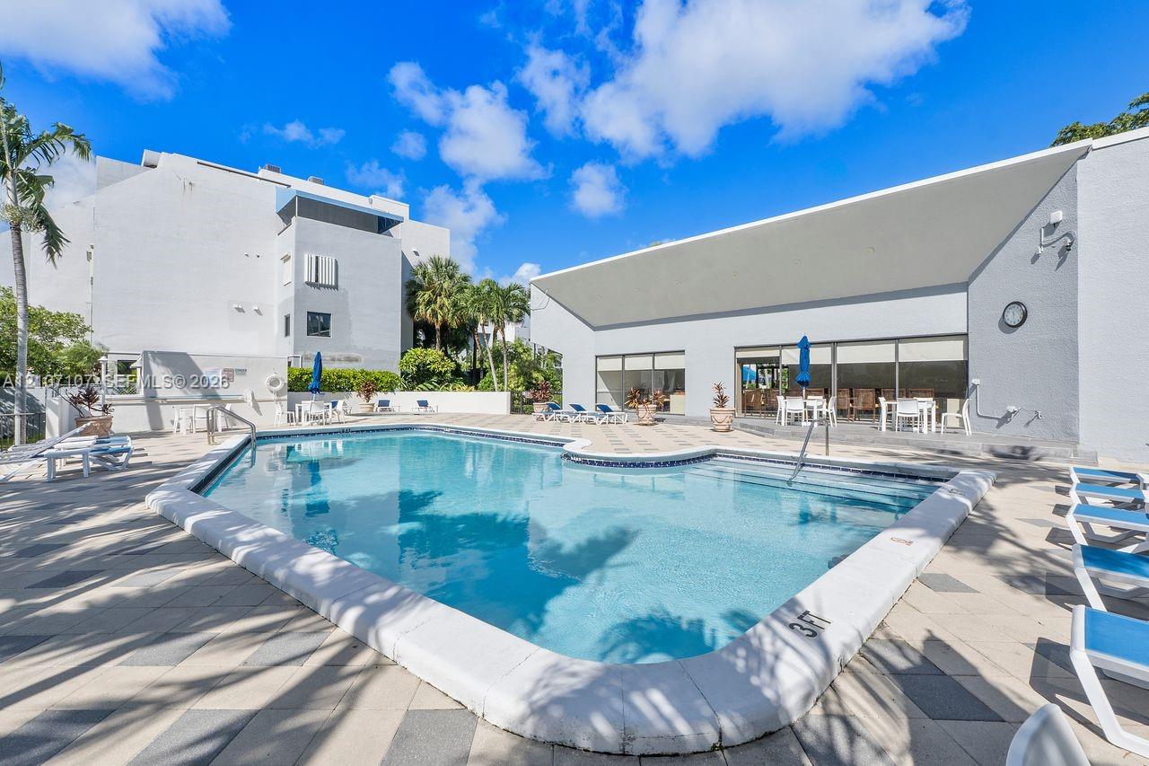 In-ground swimming pool featuring a tiled perimeter and concrete deck with patterned stone pavers