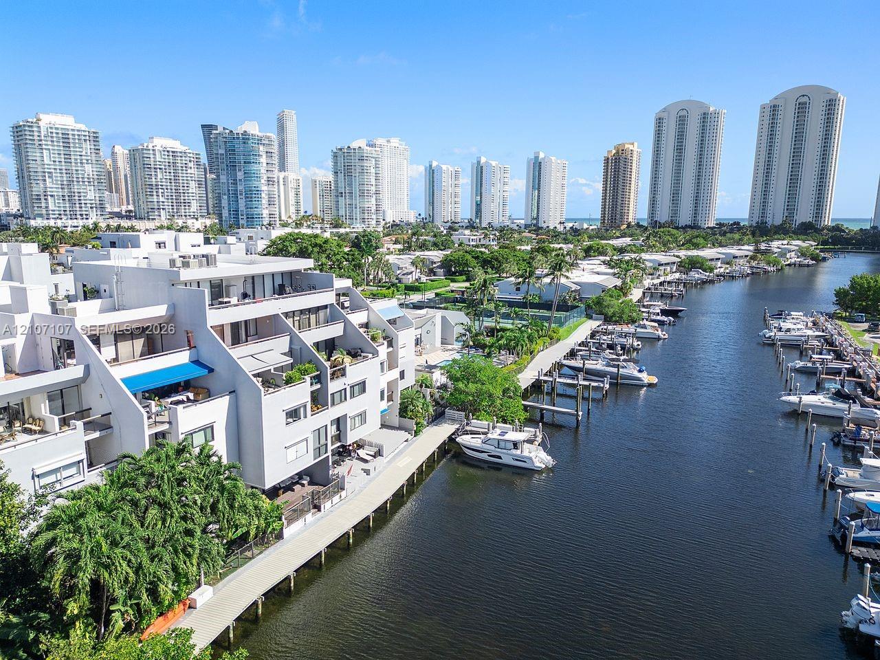 Waterfront multi-level residential structure featuring private boat slips, balconies with overhead sunshades, and concrete bulkhead walk