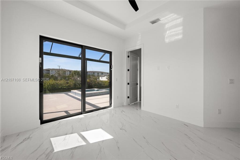 Room featuring large-format veined tile flooring, a tray ceiling, and black-framed sliding glass doors opening to a screened patio with a pool