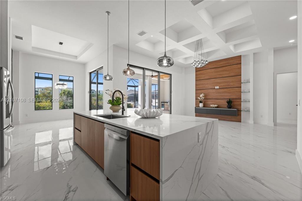 Coffered ceiling, center island with stone-finish waterfall countertop, wood-finish cabinetry, floor-to-ceiling accent wall, and polished tile flooring Coffered ceiling, center island with stone-finish waterfall countertop, wood-finish cabinetry, floor-to-ceiling accent wall, and polished tile flooring