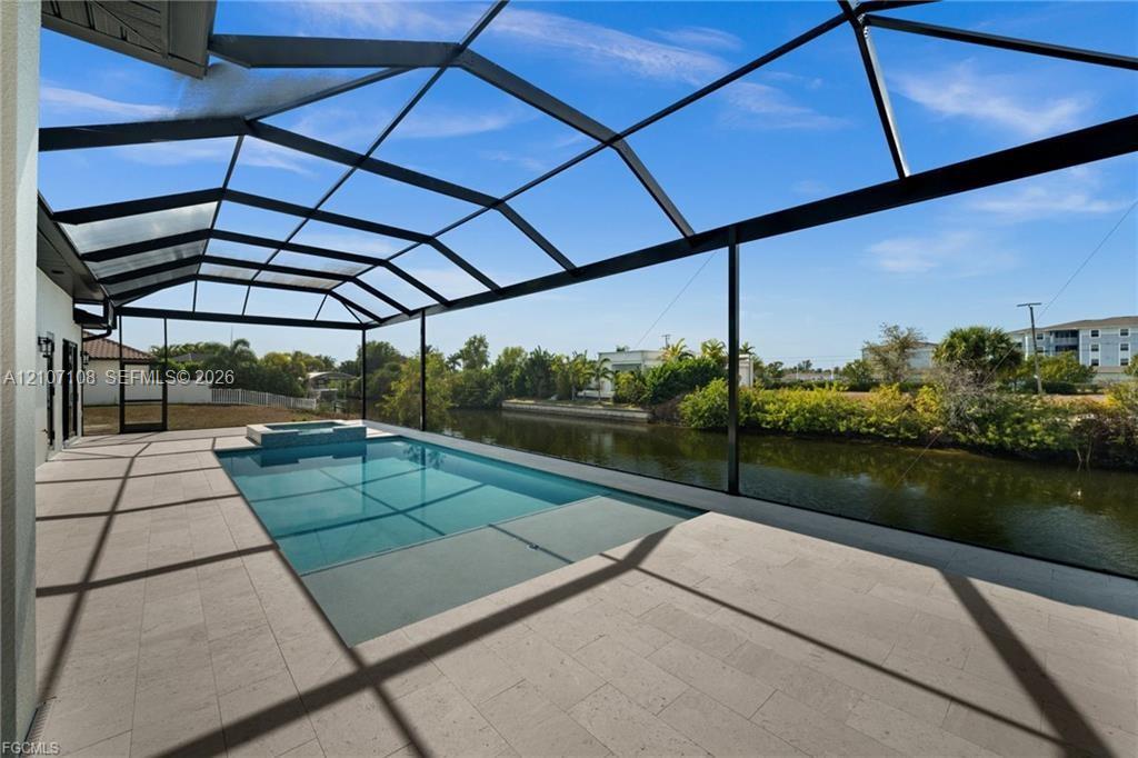 Screen-enclosed patio with large-format tile flooring, built-in swimming pool, elevated spa, and water frontage