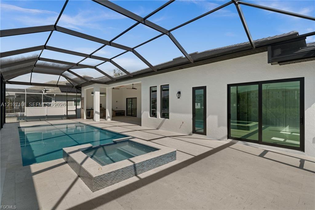 Screened-in lanai featuring a swimming pool, integrated spa with tile detailing, paved flooring, and glass sliding doors