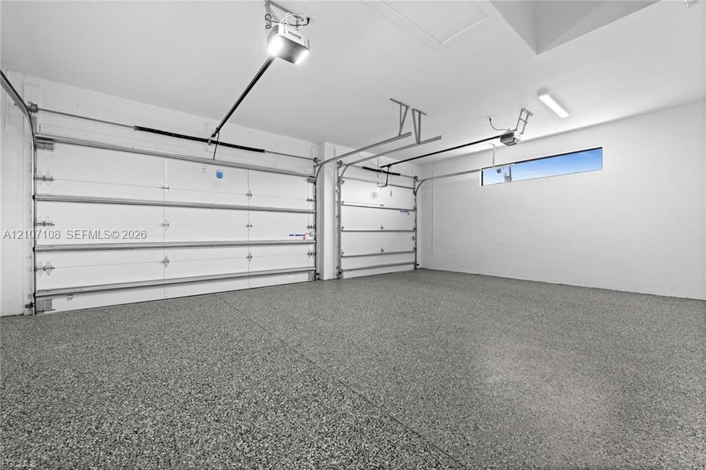 Multi-car garage featuring finished epoxy flooring, dual automatic garage door openers, and horizontal clerestory window