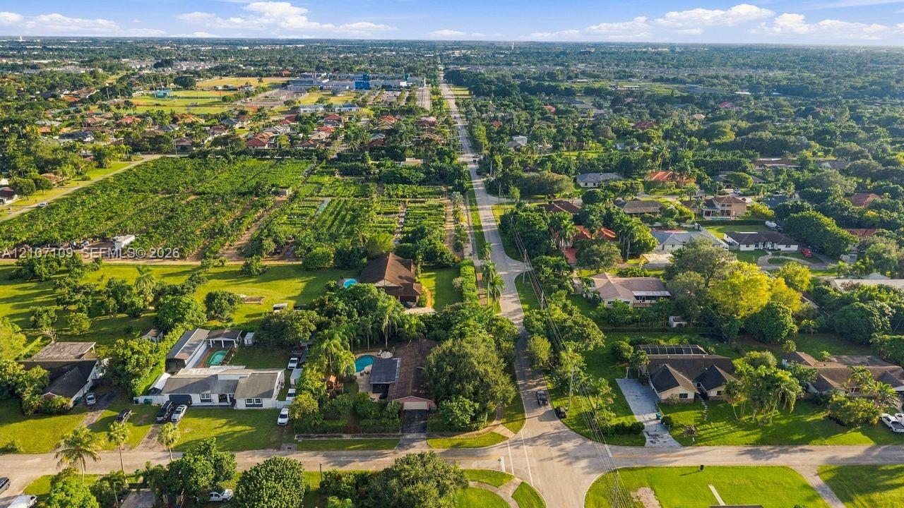 Aerial perspective featuring established residential lots, mature tree canopy, integrated swimming pools, and paved roadways