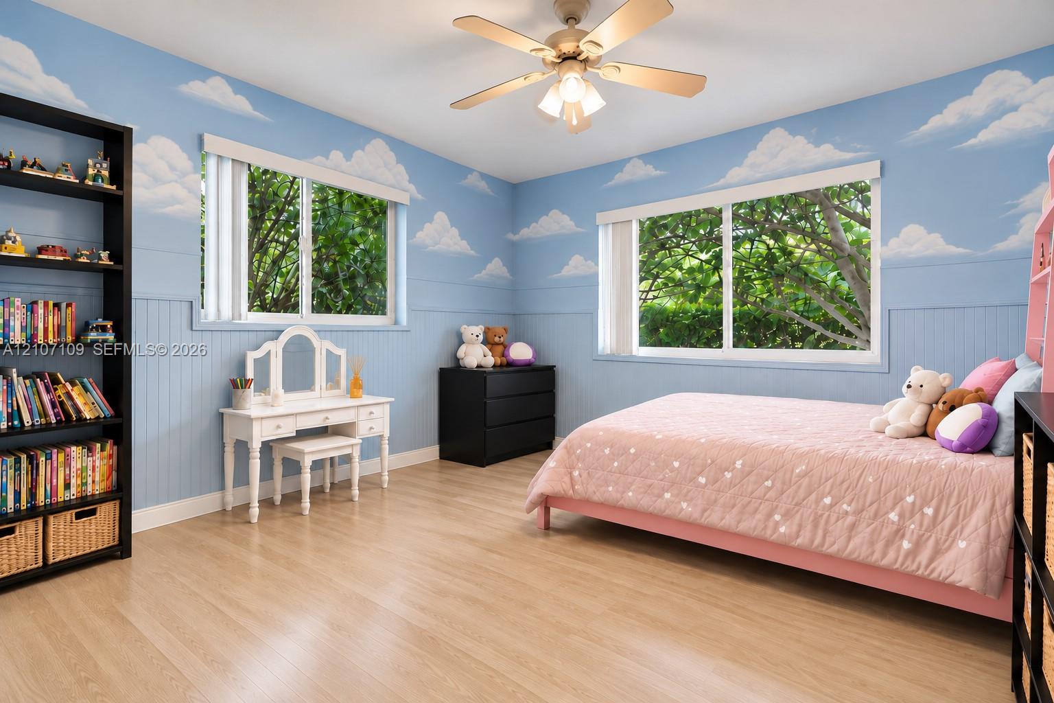 Room featuring wood-finish flooring, beadboard wall paneling, and a ceiling-mounted light fixture with integrated fan