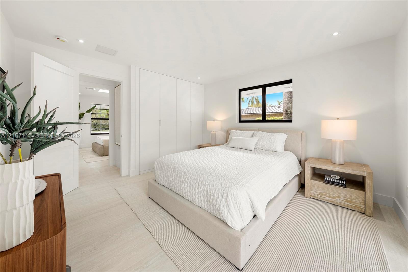 Bright room featuring recessed lighting, smooth-finish walls, wood-finish flooring, full-wall built-in cabinetry with flat-panel doors, and a black-frame window