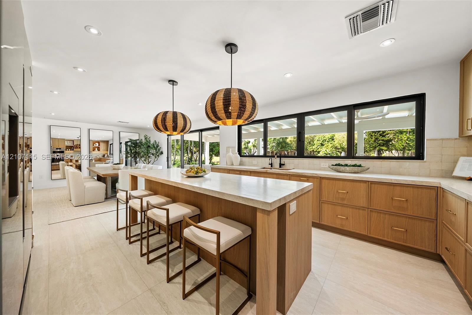 Kitchen featuring wood-finish cabinetry, a central island with a stone-top surface, recessed lighting, and large windows with black frames