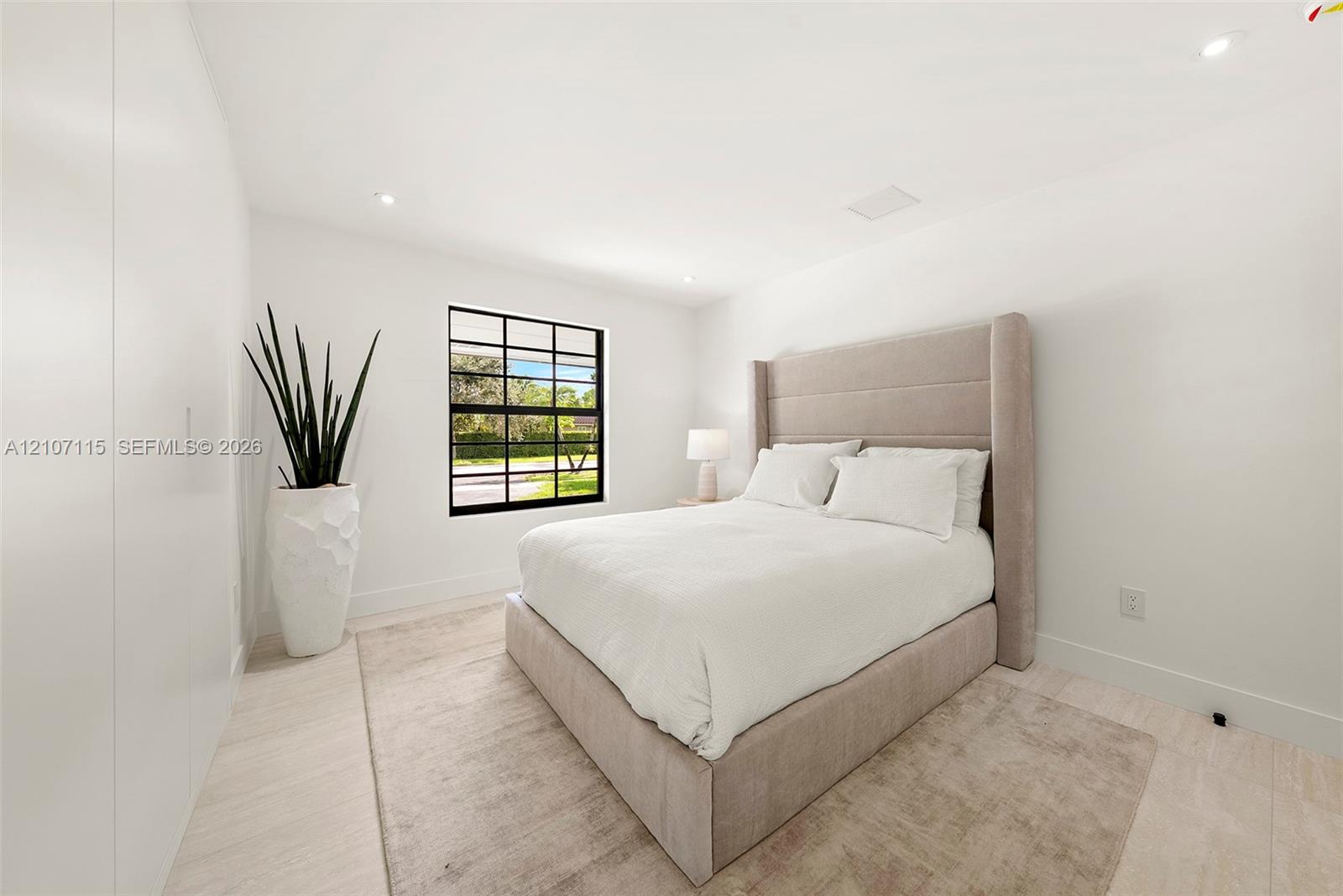Bedroom 3 Minimalist room featuring smooth white walls, recessed ceiling lighting, light-toned tile flooring, and a black-framed grid window