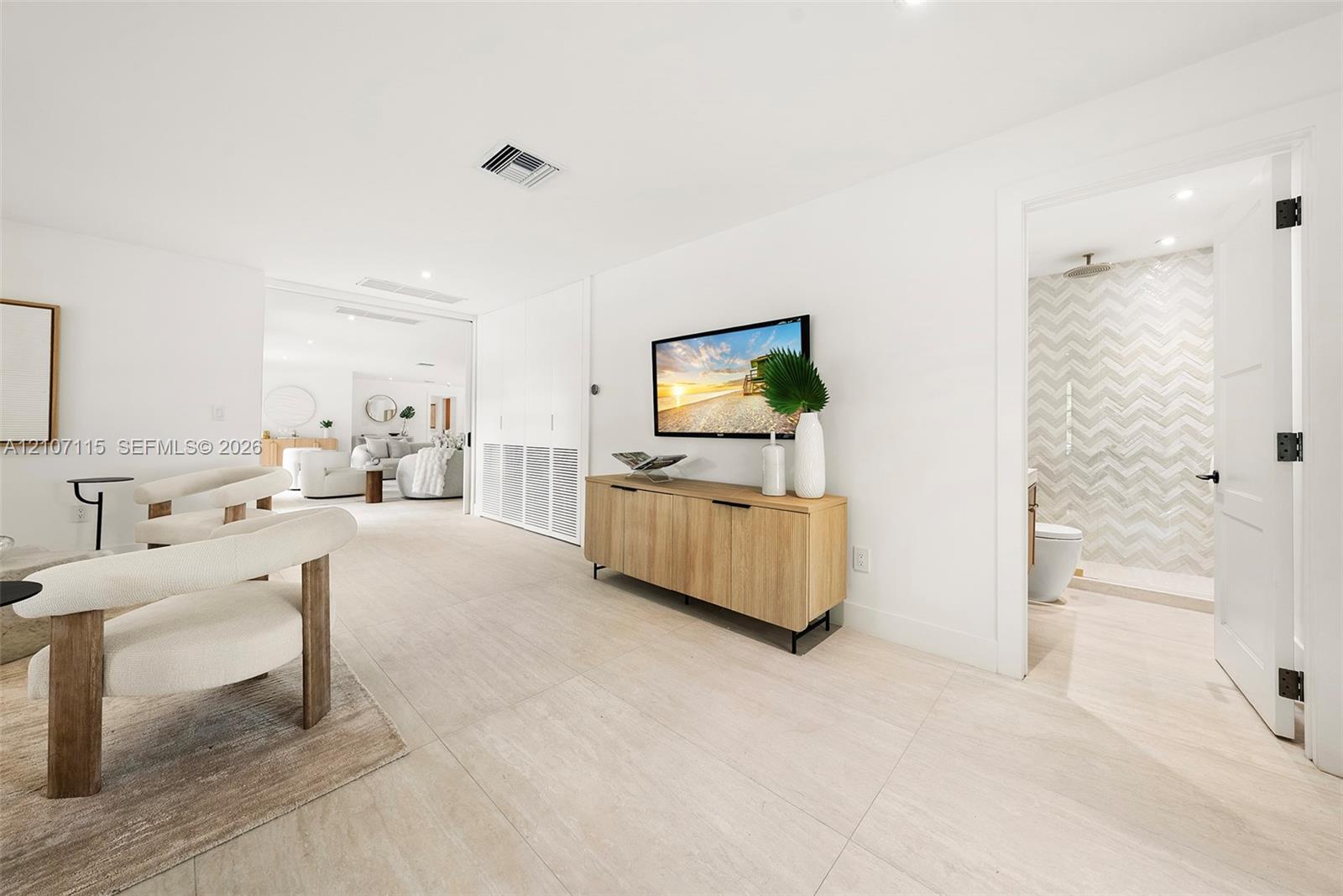 Family room/ 5 bedroom in suite Large-format tile flooring throughout featuring light neutral tones, recessed lighting, and a bathroom showcasing chevron-patterned wall tile with a rain-style shower head